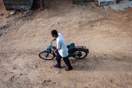 Afrique-de-lOuest;-Bénin;-Chemise-blanche;-Cotonou;-Deux-roues;-Fidjrossé;-Kaleidos;-Kaleidos-images;-La-parole-à-limage;-Mobylette;-Ombre;-Rue-sablonneuse;-Stories-Pictures;-Tarek-Charara;-Terrain-vague;-Transport;-Vue-en-plongée